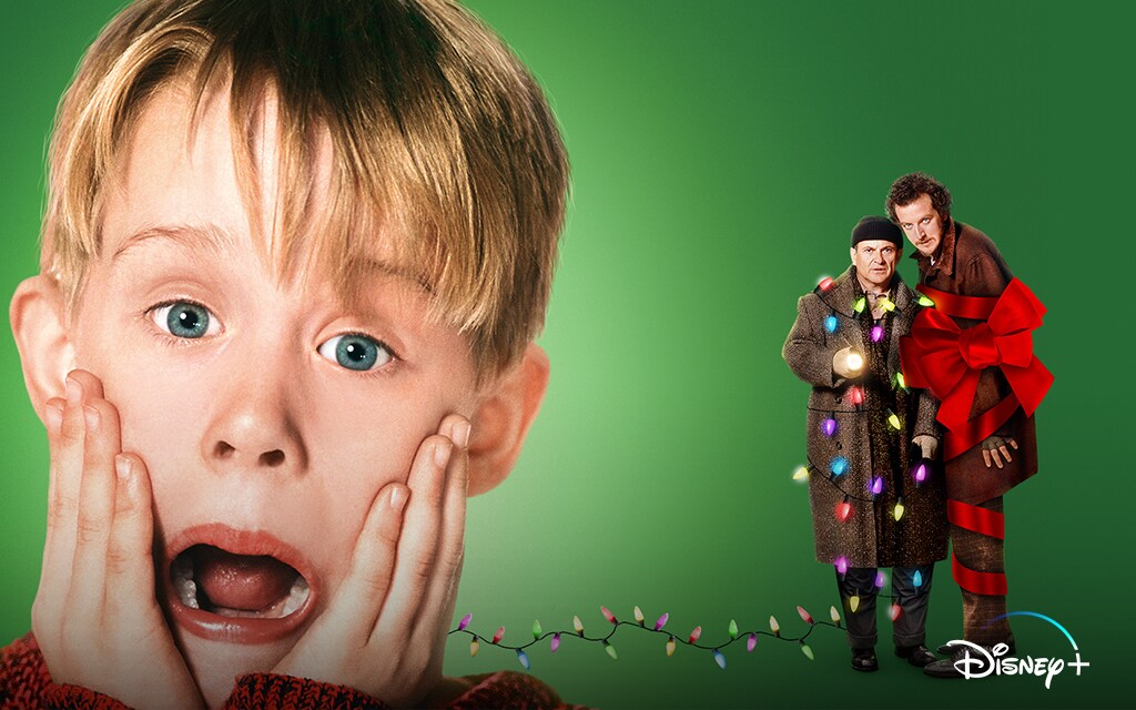 Imagem com fundo verde, à frente o ator Macaulay Culkin quando criança à esquerda, com duas mãos no rosto, (com expressão assustada). À direita há dois homens, um enrolado com luzes coloridas e o outro enrolado com uma faixa vermelha. 