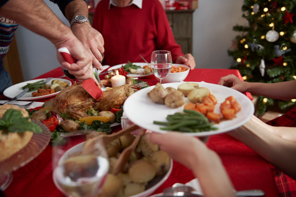 imagem de uma mesa de natal, com toalha vermelha e com alimentos mais leves, como legumes e frango.